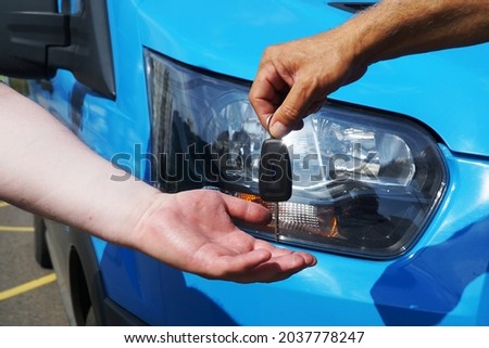 Transfer of car keys from hand to hand against the background of the headlight of the car.                               