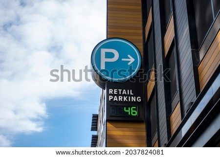 Low angle view of a baby blue digital parking sign for a parking garage in a shopping district downtown