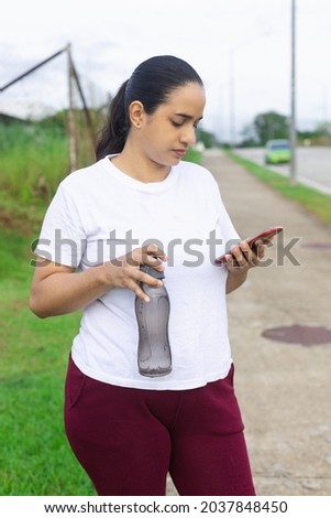 A vertical closeup of a girl checking her cell phone after drinking water 