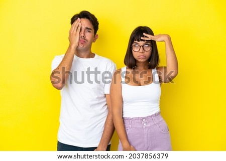 Young mixed race couple isolated on yellow background with surprise and shocked facial expression