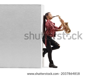 Full length profile shot of a young female saxophonist playing against a wall isolated on white background Royalty-Free Stock Photo #2037864818