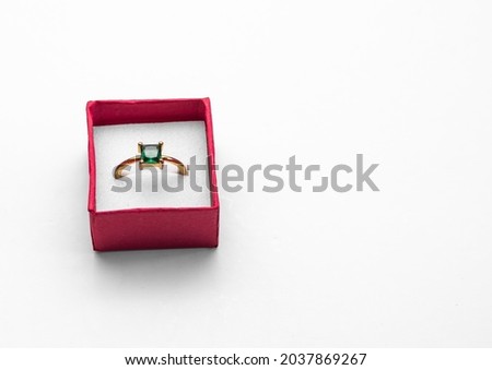 A closeup shot of a ring with a green stone on a white background