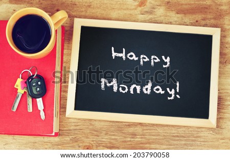 blackboard with the phrase happy monday written on it, coffee cup and car keys. filtered image.