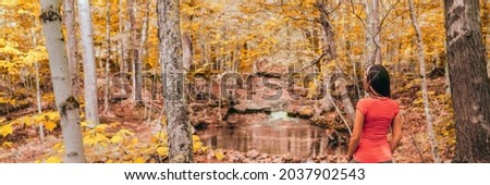 Fall forest woman hiking in autumn nature landscape panoramic. Girl enjoying outdoor environment looking at river and yellow foliage banner.