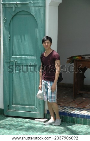 A vertical shot of a male traveler posing in front of a turquoise door in the Philippines