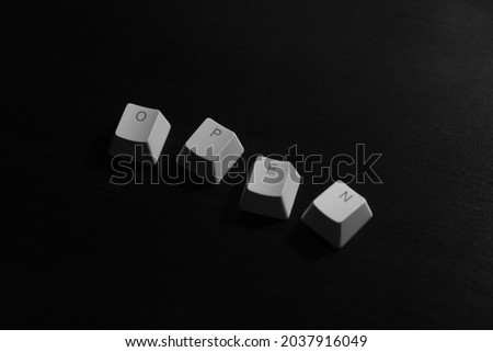 "Open" word on white keyboard keycaps on dark wood background.