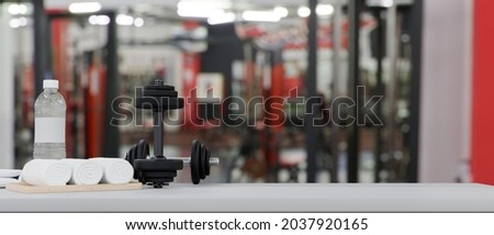 Body weight training web banner concept, dumbbells, drink bottle and towels on tabletop with space for product display over fitness gym background, 3d rendering, 3d illustration