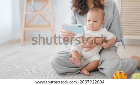 Mother showing her smartphone to her baby