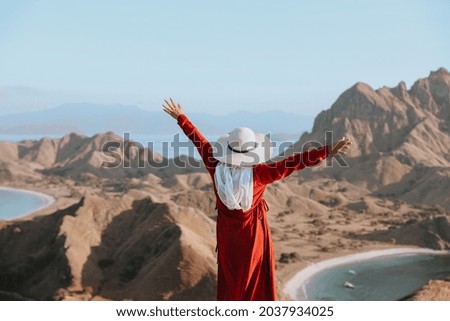 Happy woman tourist in summer hat enjoying vacation on the top hill