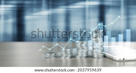 smartphone screen next to growing piles of coins and chart positive indicators in his business Royalty-Free Stock Photo #2037959639