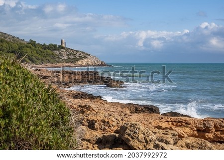 A closeup shot of huge, beautiful sea waves touching the rocky coast with a blue sky background