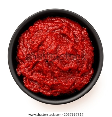 Tomato paste in a black ceramic bowl isolated on white. Top view. Royalty-Free Stock Photo #2037997817