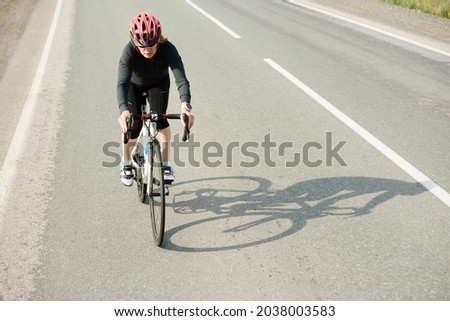Woman cycling on countryside summer sunny road or highway during sports training