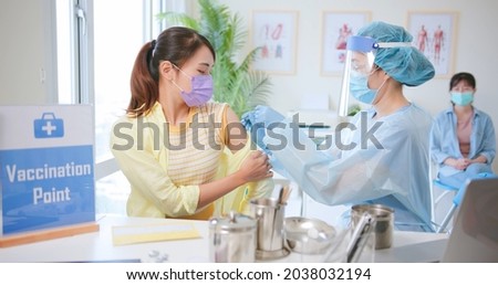 asian woman wearing face mask receiving coronavirus vaccine in hospital