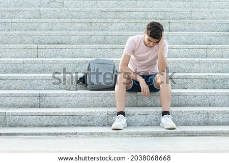 Sad and frustrated hispanic teenager sitting on stairs and holding his head. Anxiety and depression in adolescence concept. Royalty-Free Stock Photo #2038068668