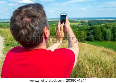 Young backpacker man taking selfie picture using smartphone.cloudy sky weather mountain summer range.Landscape summer background.Active sport backpacking healthy lifestyle concept.