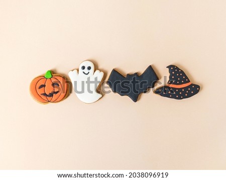 Various Halloween gingerbread cookies - Jack O'Lantern, ghost, bat and black hat on beige background. Minimal Halloween concept. Top view. Copy space