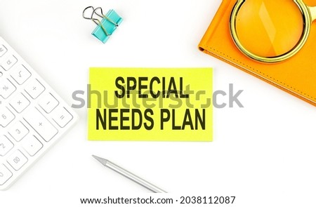Sticker with the text SPECIAL NEEDS PLAN on white background, near calculator and notebook