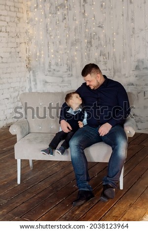 father and son 3 years old are sitting on the sofa in the living room at home and hugging