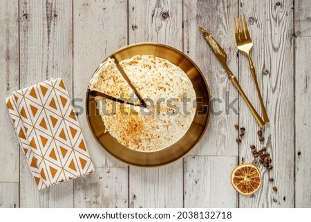 Top view image of carrot cake on plate and golden cutlery with coffee beans, dried orange, tea towel on wooden table