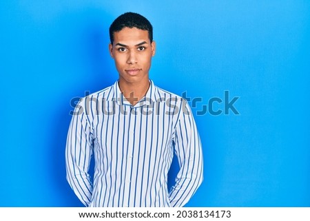 Young african american guy wearing casual clothes relaxed with serious expression on face. simple and natural looking at the camera. 