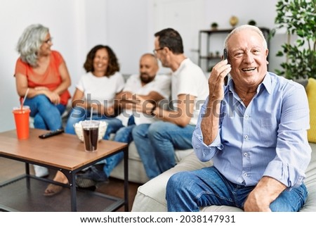 Group of middle age friends sitting on the sofa speaking. Man smiling happy talking on the smartphone at home.