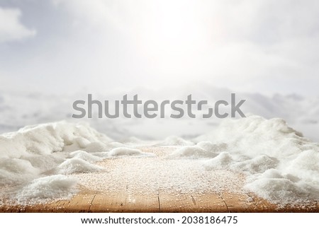 Fresh white snow on a wooden table against the backdrop of a bright mountain landscape on a beautiful winter day 