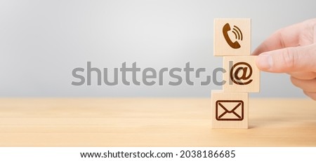 Hand Stacking wood Blocks with Icons mobile phone, email envelope telephone and e-mail address Against gray Background. Wooden cubes with symbol telephone, email, address. Contact us