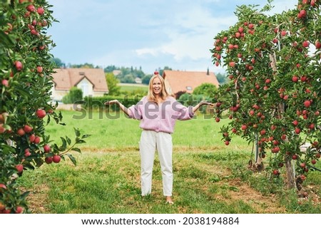 Outdoor portrait of happy young woman in countryside, female model placed apple on her had, funny fashion lady