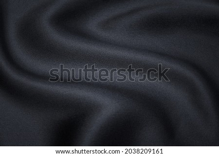 Abstract texture of natural black or dark gray color fabric as concept background. Fabric texture of natural cotton or linen, silk or satin, wool or jersey textile material. Luxurious dark background. Royalty-Free Stock Photo #2038209161