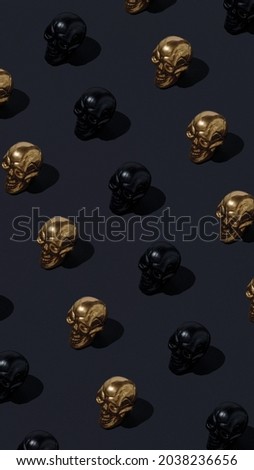 A pattern of black and golden painted human skulls isolated on a black background. Creative Halloween or Day of the Dead concept. Minimal spooky cult aesthetic. Luxurious horror texture.