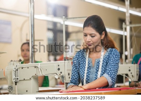 Woman textile worker using sewing machine on production line Royalty-Free Stock Photo #2038237589