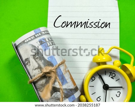 Business concept.Text Commission writing on notepaper with clock and fake money on green background.