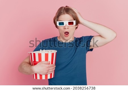 Photo of young guy hold popcorn paper box wear 3d glasses amazed shocked surprised watch thriller isolated pink color background