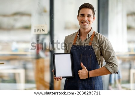 Portrait of Starting small handsome man businesses owners showing tablet with blank screen at coffee shop.
