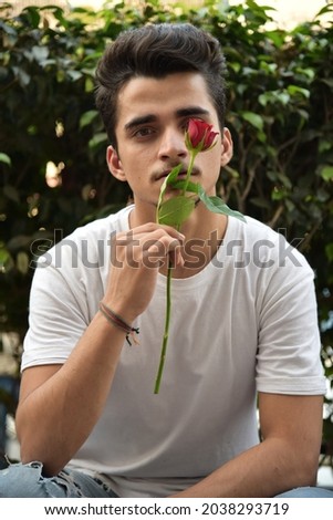 An attractive Southeast Asian male holding a stem of red rose Royalty-Free Stock Photo #2038293719