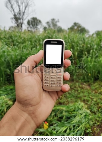 Farmer holding keypad mobile phone in hand with blank white screen Royalty-Free Stock Photo #2038296179