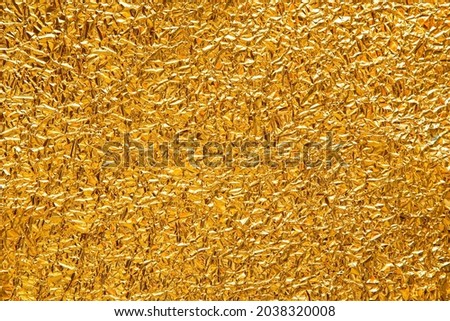 High resolution detailed festive texture of a crumpled golden foil, material background close up view