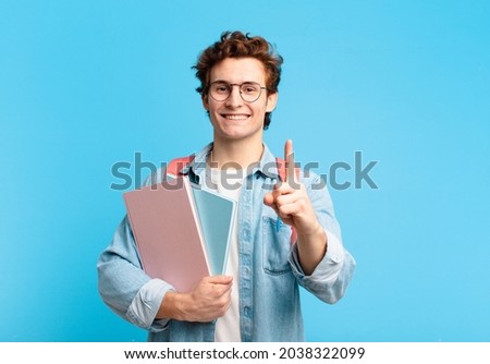 young student boy smiling proudly and confidently making number one pose triumphantly, feeling like a leader Royalty-Free Stock Photo #2038322099