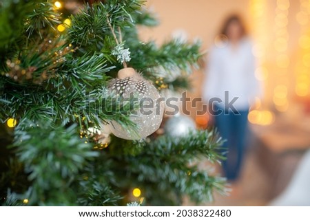 Christmas tree decorated with balls and a blurred female silhouette in the background. Christmas concept. Woman out of focus