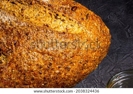 Slice of rustic natural yeast-free bread with flax, poppy seeds, sesame seeds, millet, pumpkin and sunflower seeds, on a black background, hard light, photo in a low key, close up