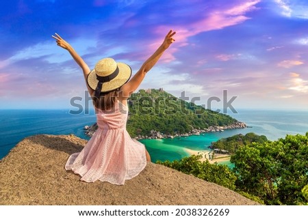 Woman traveler wearing pink dress and straw hat at Nang Yuan Island, Koh Tao, Thailand in a summer day