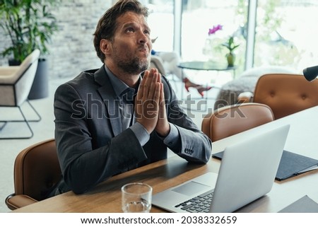 Worried Business Man Praying at Work.
Stressed businessman expecting results and praying while sitting at desk and working on laptop computer in the office. Royalty-Free Stock Photo #2038332659