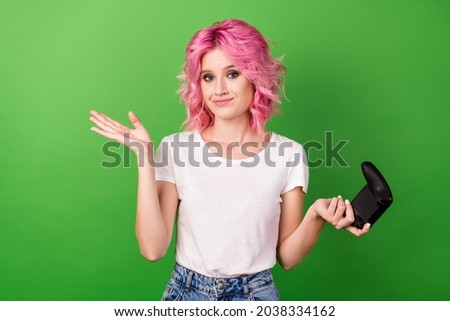 Photo portrait young girl pink hair playing video games keeping joystick unsure isolated vivid green color background