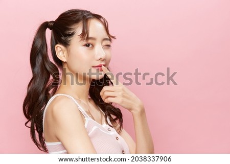 Pink background portrait of a young Asian woman with pigtails Royalty-Free Stock Photo #2038337906