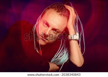 Handsome man with interesting braids on a black background, shot with mixed light.