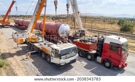 Transportation of oversized cargo.Two truck cranes load an oversized cistern onto a transport truck. Royalty-Free Stock Photo #2038343783