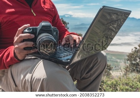 Man working with laptop and camera on the top of mountain