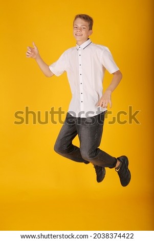 a young handsome guy in a white shirt gray trousers a schoolboy jumps yellow background