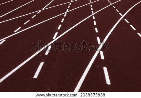 All-weather running track, white dash and solid lines crosses on brown rubber racetracks, selective focus. Racing curve on runner lanes surface, depth of field. Competition, pace abstract concept. Royalty-Free Stock Photo #2038375838